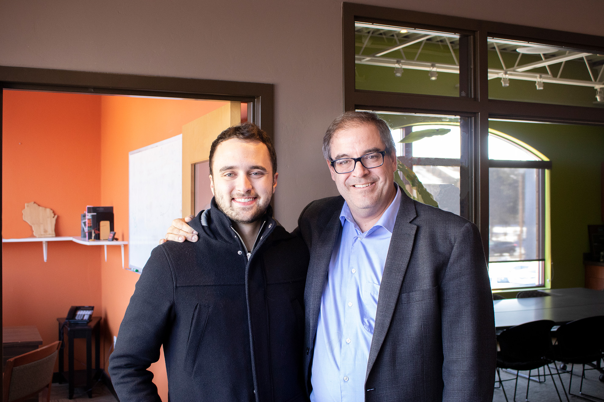 Joe Kiedinger and Alex Bougie standing in office lobby for a photo